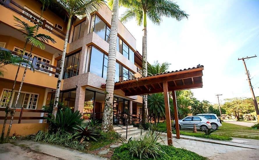 Entrada do Amarilis, uma construção com três andares com detalhes em vidro, e um jardim com estacionamento