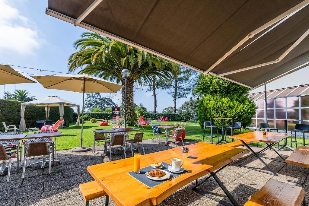 Área de lazer ao ar livre do Hotel ibis Porto Gaia mesas com cadeiras a frente.
