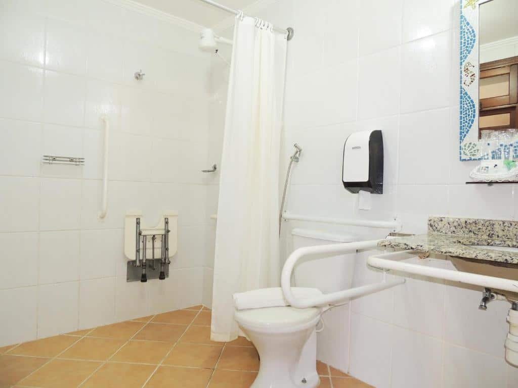 Banheiro adaptado da Pousada Mosaico Brasil – Maresias com barras de apoio, pia mais baixa e box que não tem vidro apenas cortina