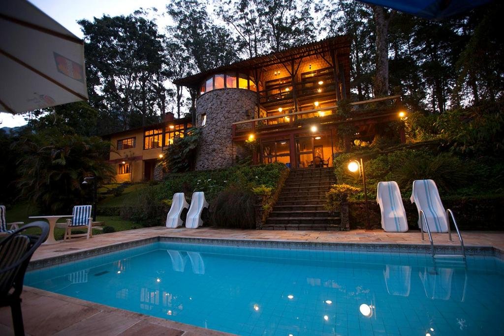 Piscina da pousada bromélia sabiá & cia em Teresópolis e ao fundo a hospedagem iluminada.