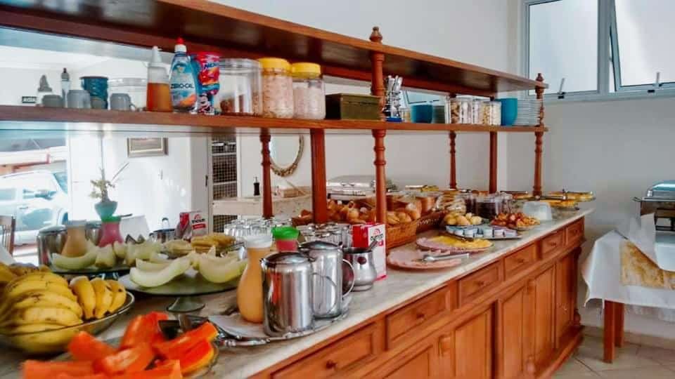 Móvel de madeira com diversos itens de café da manhã como frutas, pães, sucos e leite.