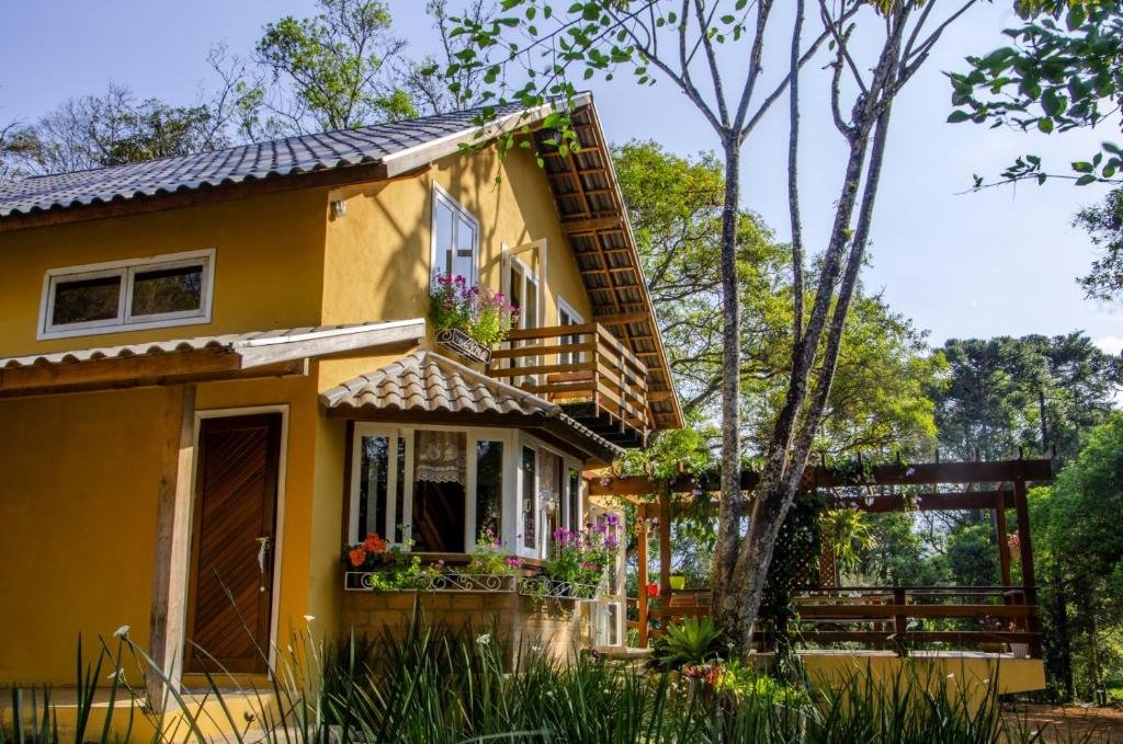 Exterior da casa amarela e de dois andares, chamada Casa De Férias e Hospedagem Ana Lua. Na direita dela ainda há um quiosque.