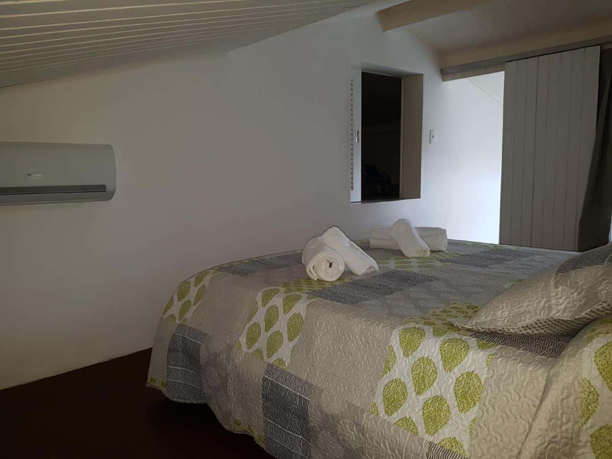 Quarto da Casa- Maresias 3 minutos da praia. Uma cama de casal está no meio. Na parede em sua frente há um ar-condicionado e uma janela.
