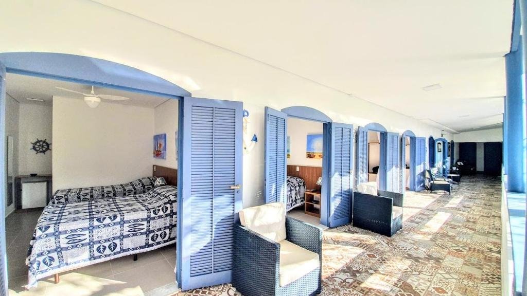 Vista da frente dos quartos do Brisa do Mar Barê Praia Hotel durante o dia com várias portas que dá acesso aos quartos com cama. Representa airbnb em São Sebastião.