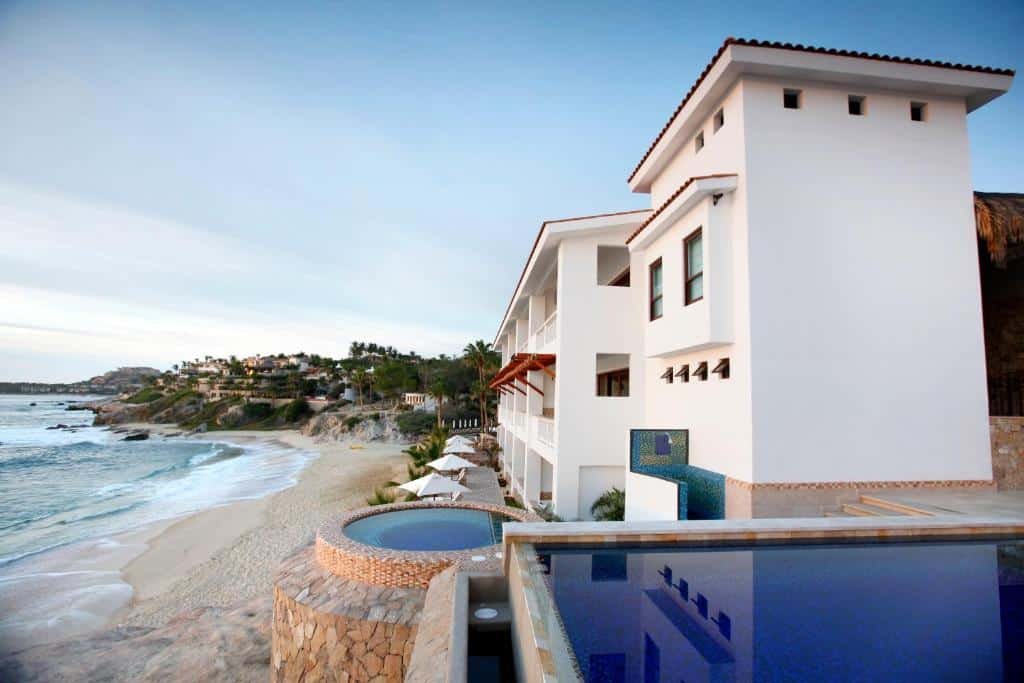 Frente do Cabo Surf Hotel à beira-mar com piscina na frente e céu claro.