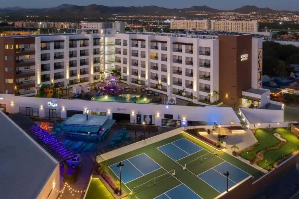 Vista de cima do Medano Hotel and Suítes com quadra de esportes, piscina e varadas com sacada.
