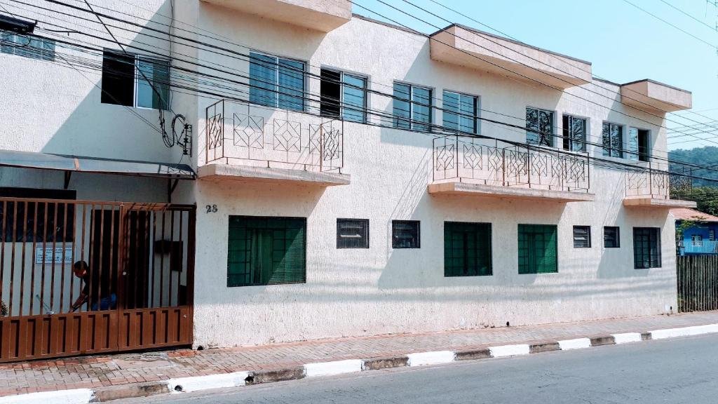 Frente da Hospedaria São Benedito, uma das pousadas em Guararema, com parede rosa claro e várias janelas