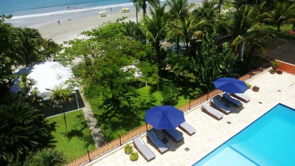 Piscina do Hotel Porto Di Mare com um pequeno gramado que leva a praia