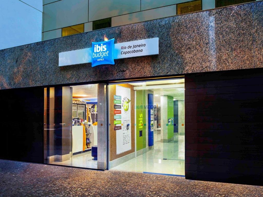 Fachada do hotel com escrita em azul e duas portas de vidro.