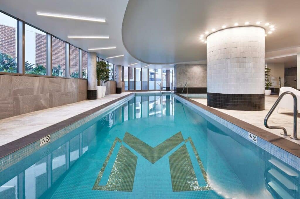 Uma piscina coberta no Meriton Suites George Street, Parramattael. Do lado esquerdo janelas.