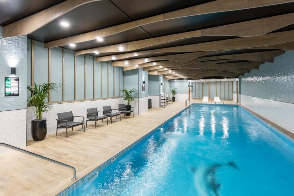 Piscina coberta do Meriton Suites Sussex Street. Do lado esquerdo cadeiras e vasos de plantas.