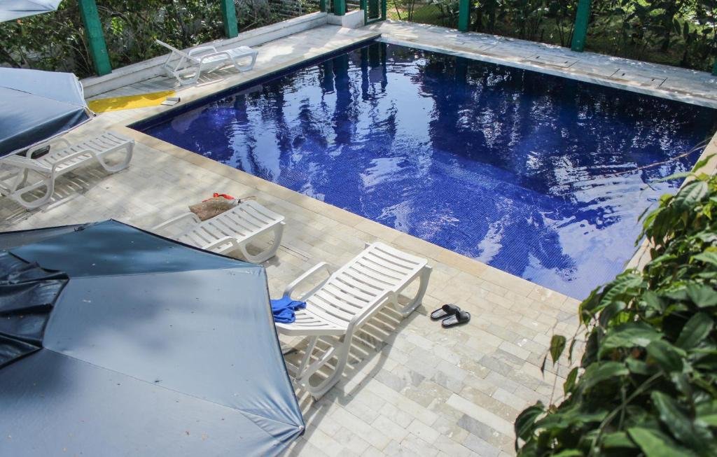 Piscina em Alapage em Toque-Toque Pequeno, uma piscina quadrada, cercada por espreguiçadeiras, guarda-sol, e algumas árvores e vegetação