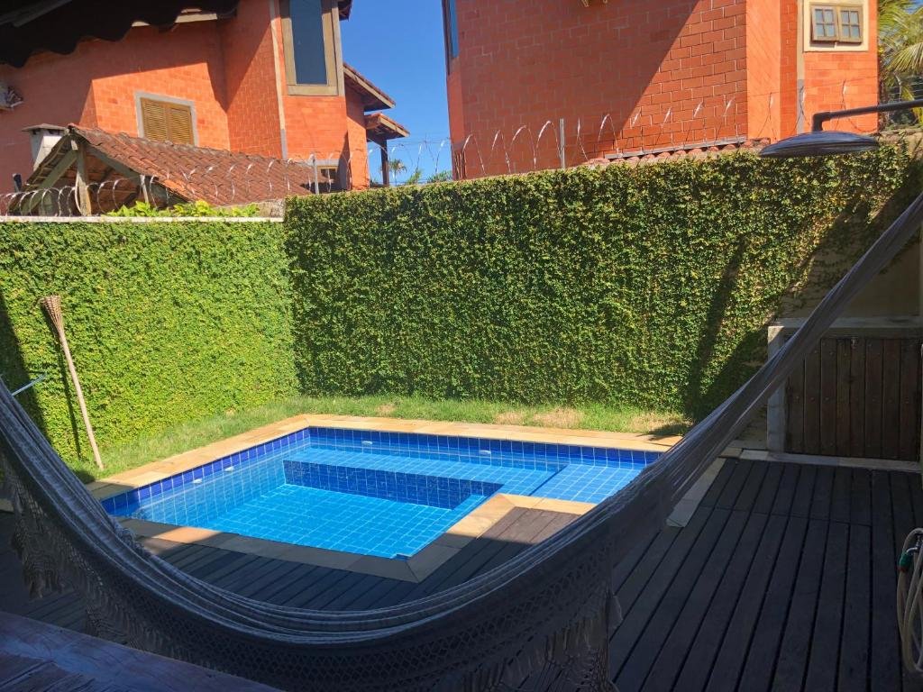 Vista da área de estar da Casa com Piscina Aquecida Privativa durante o dia com uma rede a frente e ao fundo a piscina.