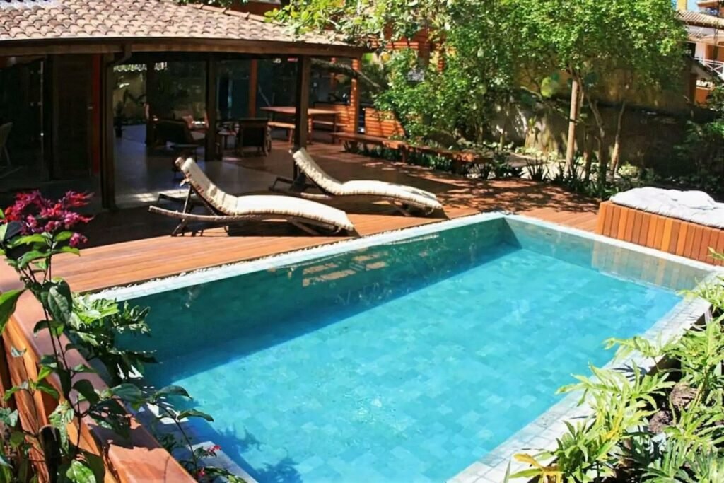 Piscina da Casa Tubarão – A Melhor durante o dia com piscina a frente e do outro lado cadeiras e mais ao fundo a estadia.