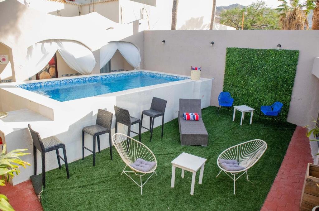 Vista da piscina do Donjuan By Melida Hotel com área de lazer, o local conta com várias cadeiras colocadas na grama. Representa hotéis em Los Cabos.