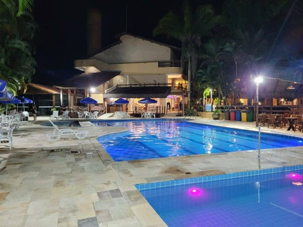 Piscina do Flat Amarilis Apartamento 103 de noite com iluminações indiretas, o deck com espreguiçadeiras
