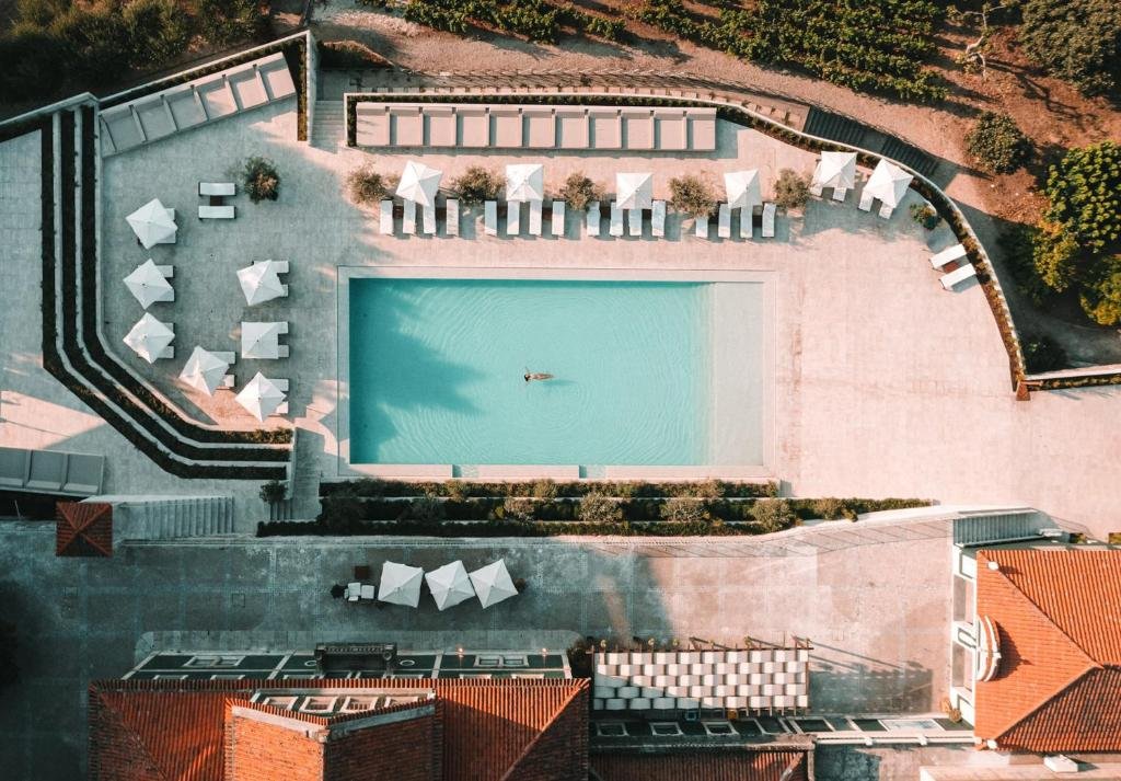 Vista de cima do Lamego Hotel & Life durante o dia com piscina no centro em volta da piscina cadeiras com guarda-sóis.