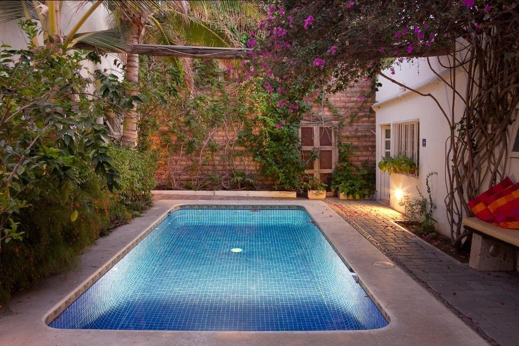 Vista da piscina do Los Milagros Hotel com plantas do lado direito.