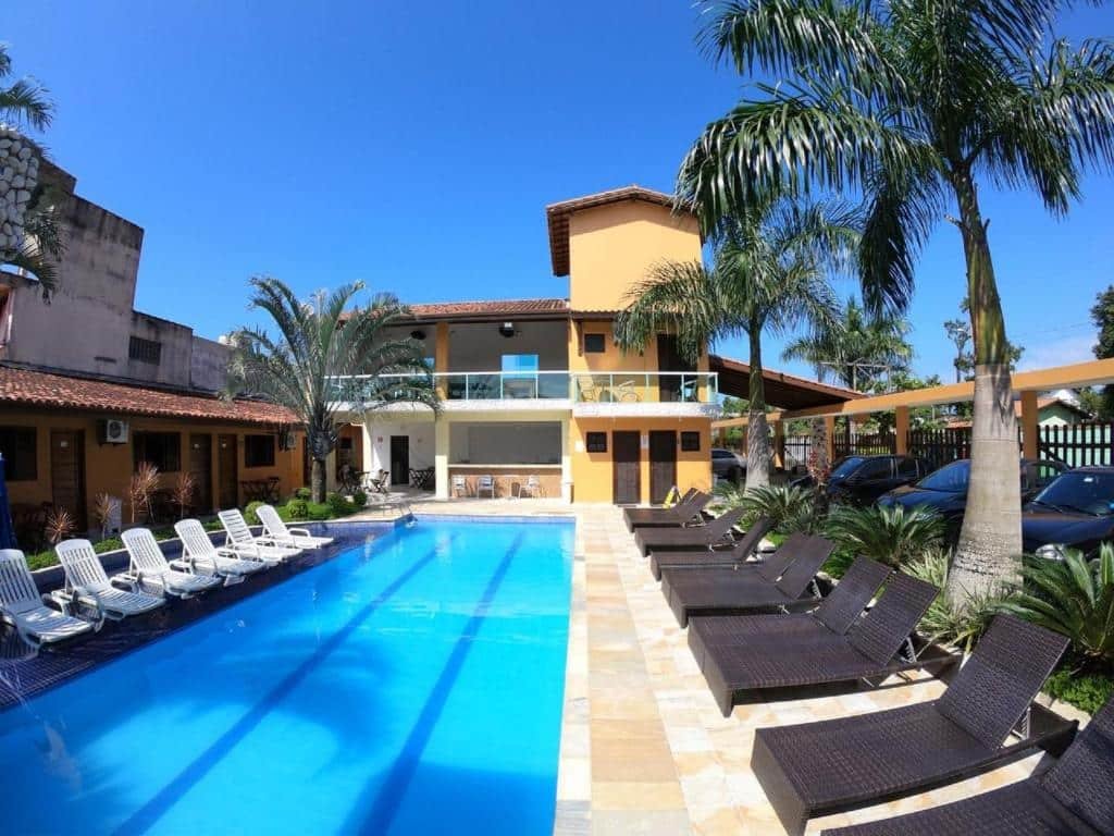 Piscina da Pousada Acqua Bella, com um deck cercado por palmeiras e espreguiçadeiras