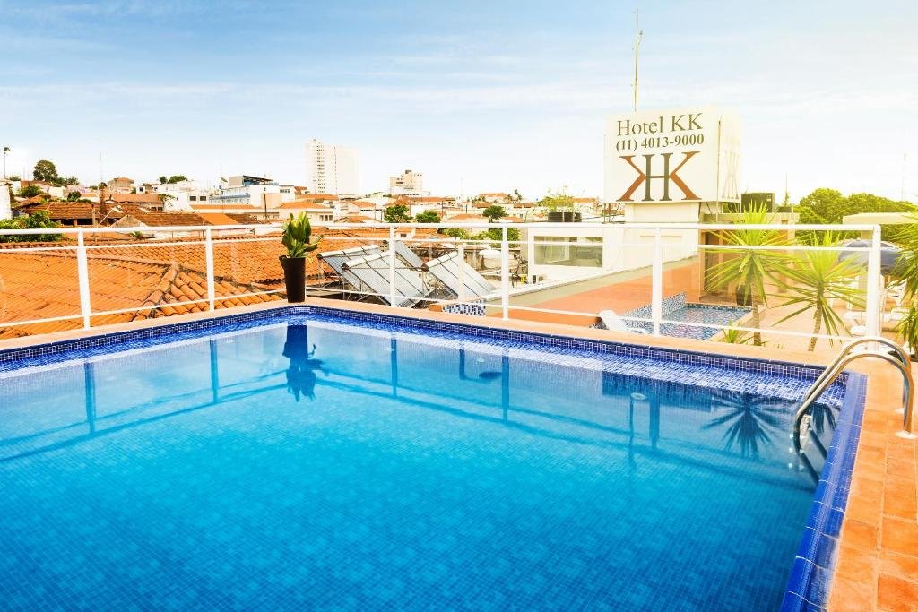 Piscina azul no terraço com telhados avermelhados em volta.
