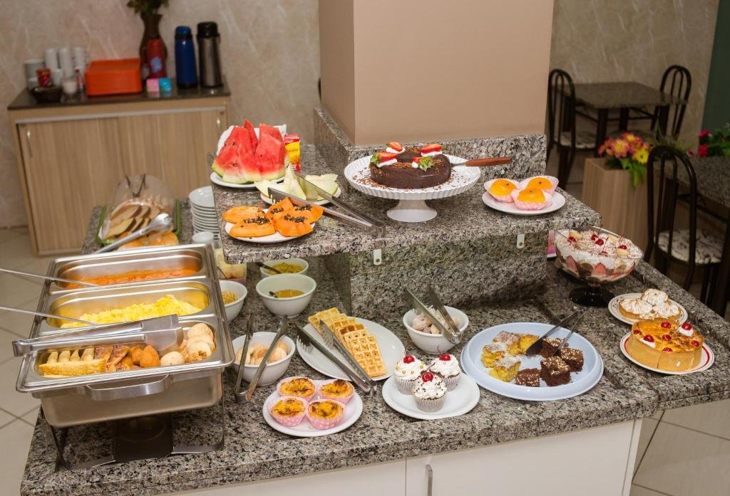 Balcão com uma grande variedade de alimentos do café da manhã da Pousada Center.