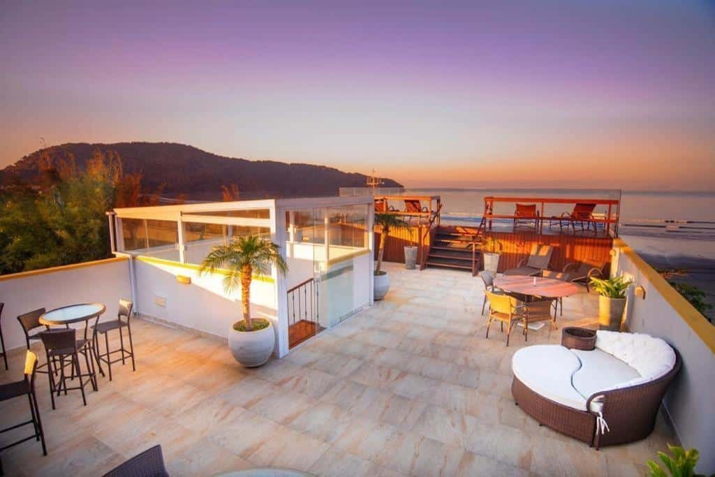 Vista da cobertura da Pousada Conca di Mare - Restaurante - Pé na areia com serviço de praia, com vista para o mar e a praia, com muitas cadeiras, sofás e mesas