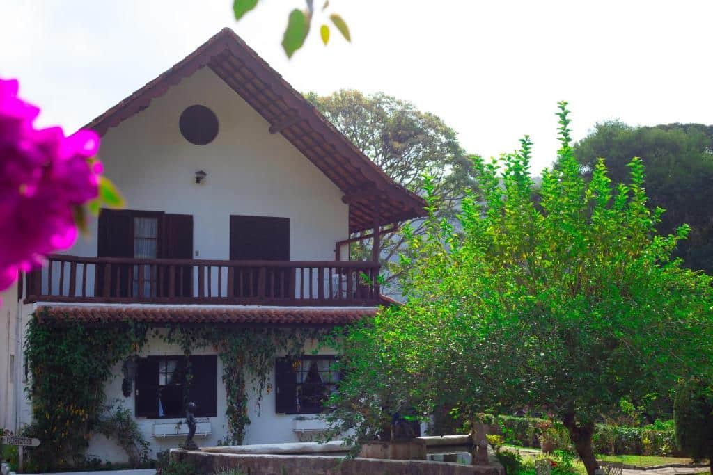 Fachada da pousada taverna do golf em Teresópolis com árvores verdes durante o dia.