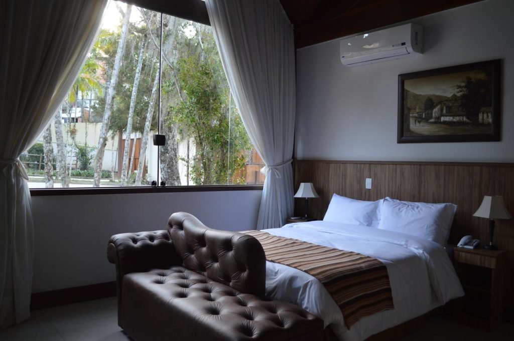 Quarto com janela de vidro da pousada Terê Parque em Teresópolis.