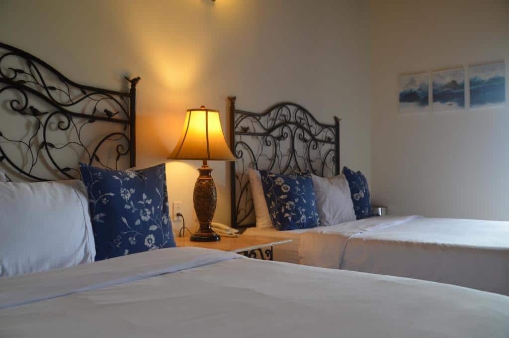 Quarto do Hotel Boutique Vista La Ribera com duas camas de solteiro e uma cômoda com luminária no meio das camas.