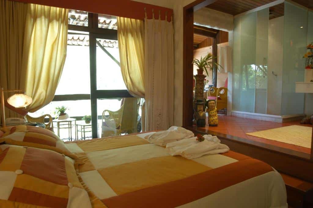 Quarto da pousada bromélia sabiá & cia com cama de casal, degraus que leva para outra parte do quarto e uma porta de vidro para a varanda, ilustrando post pousadas em Teresópolis.