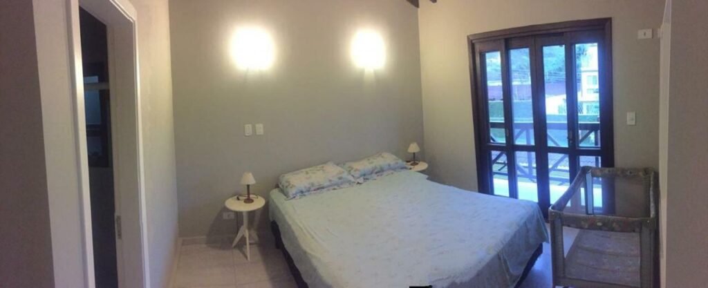 Quarto da Casa com Piscina Aquecida Privativa com cama de casal do lado direito da imagem, com uma cômoda em cada lado da cama com luminária.