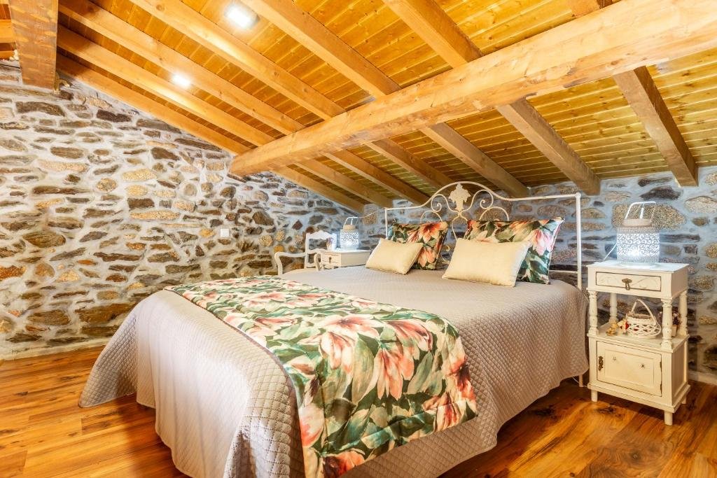 Quarto do Casa do Feitor - Douro - Quinta da Cabrida com cama de casal no centro e duas cômodas ao lado da cama com luminária. Representa hotéis no Vale do Douro.