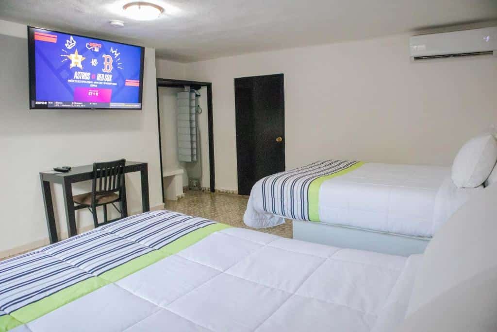 Quaro do Donjuan By Melida Hotel com duas camas amplas de solteiro, TV em frente as camas pendurada na parede, com mesa de trabalho embaixo da TV.