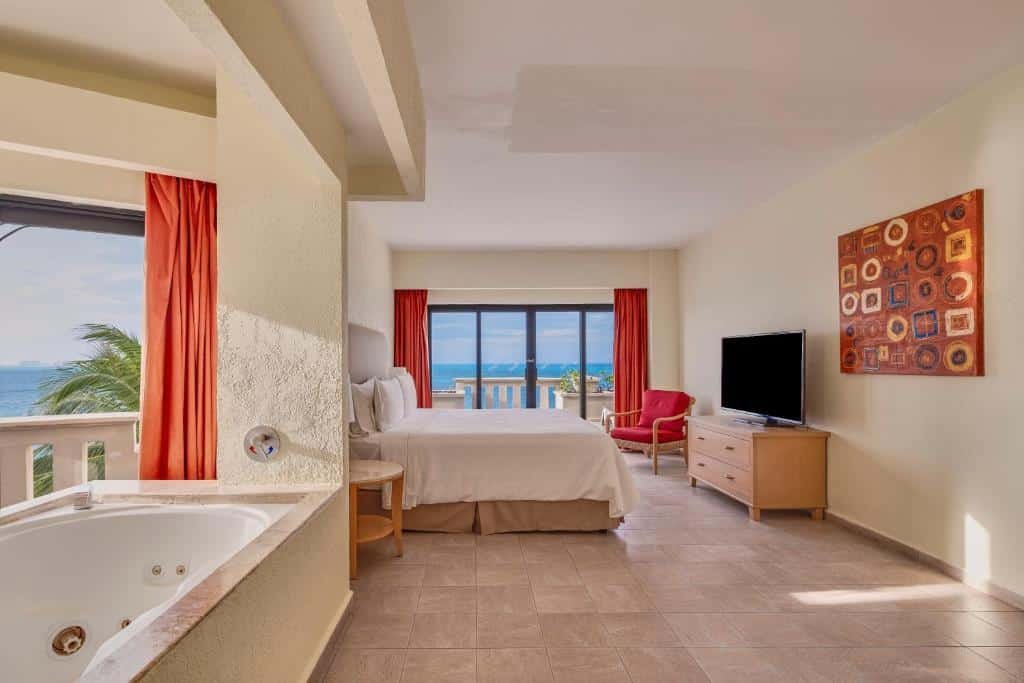 quarto do Fiesta Americana Villas com uma cama de casal, uma varanda particular em frente ao mar e uma banheira de hidromassagem