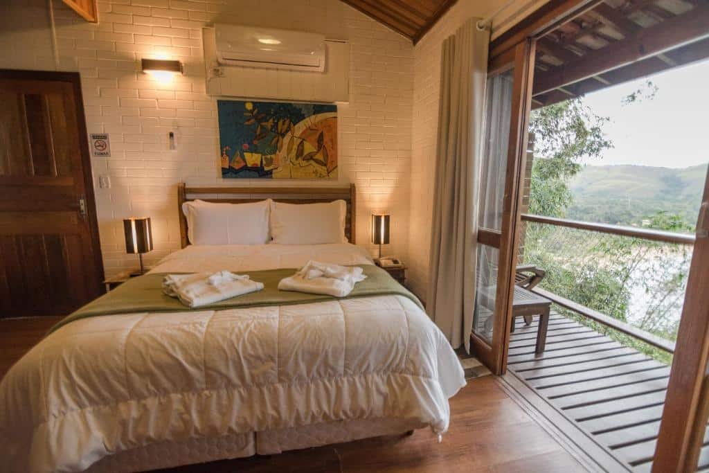 Quarto de casal com uma cama, abajures, um quadro sob a cama, uma sacada com frente para a natureza em Ilha de Toque Toque Boutique Hotel & Spa