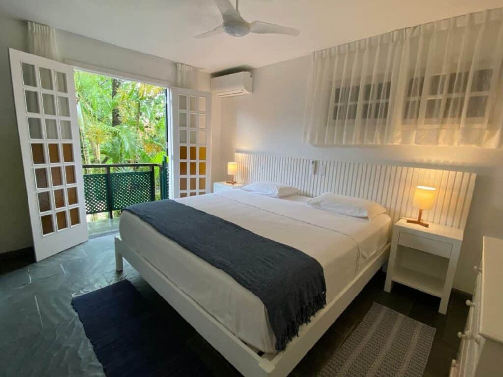 Quarto da Juquehy – Condomínio de Frente para o Mar com cama de casal do lado direito da imagem com uma cômoda em cada lado com luminária. Representa airbnb na Barra do Sahy.