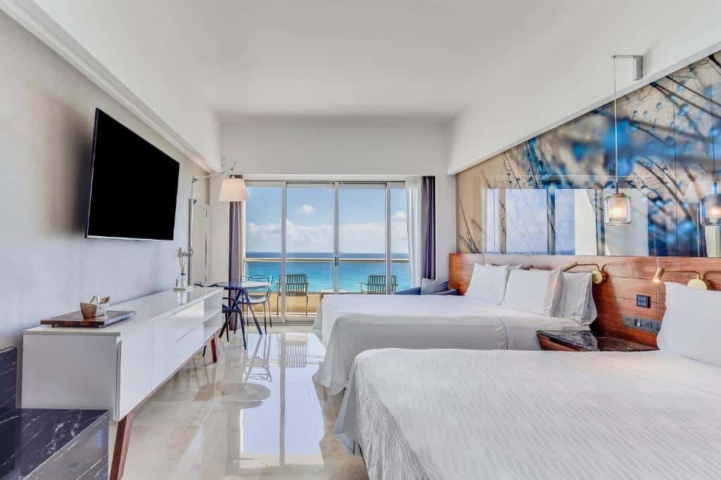 quarto do Live Aqua Beach Resort Cancun com duas camas de casal e uma varanda particular com vista do mar