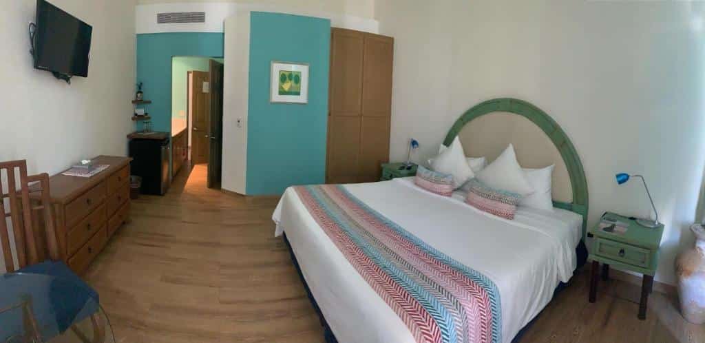 Quarto do Marisol Hotel Boutique com cama de casal, duas cômodas ao lado da cama, TV e cômoda em frente da cama.