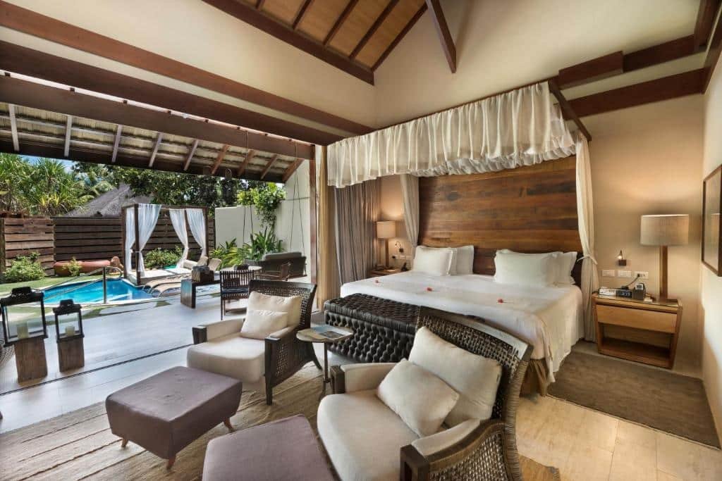 Quarto do NANNAI Muro Alto com uma varanda que inclui uma piscina privativa, com um bangalô com almofadas, alguns itens de madeira e algumas plantas, dentro do cômoda, há duas poltronas e uma cama de casal, com decoração rústica