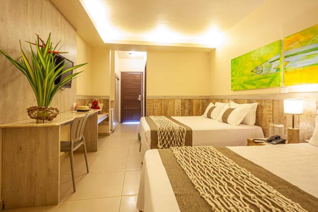 Quarto do Ocaporã Hotel All Inclusive com uma cama de casal, uma de solteiro, uma mesa de trabalho com cadeira, uma televisão e alguns quadros na parede