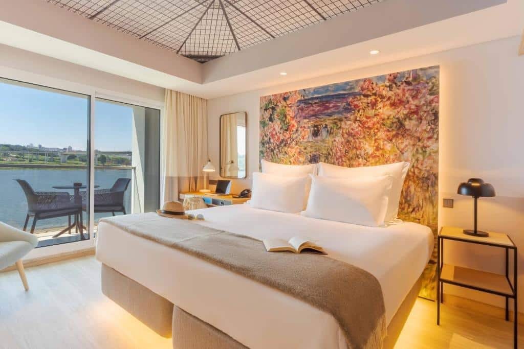 Quarto do Porto Palácio Hotel by The Editory com cama de casal do lado direito da imagem uma cômoda do lado direito da cama e do lado esquerdo uma mesa de trabalho. Representa melhores hotéis no Porto.