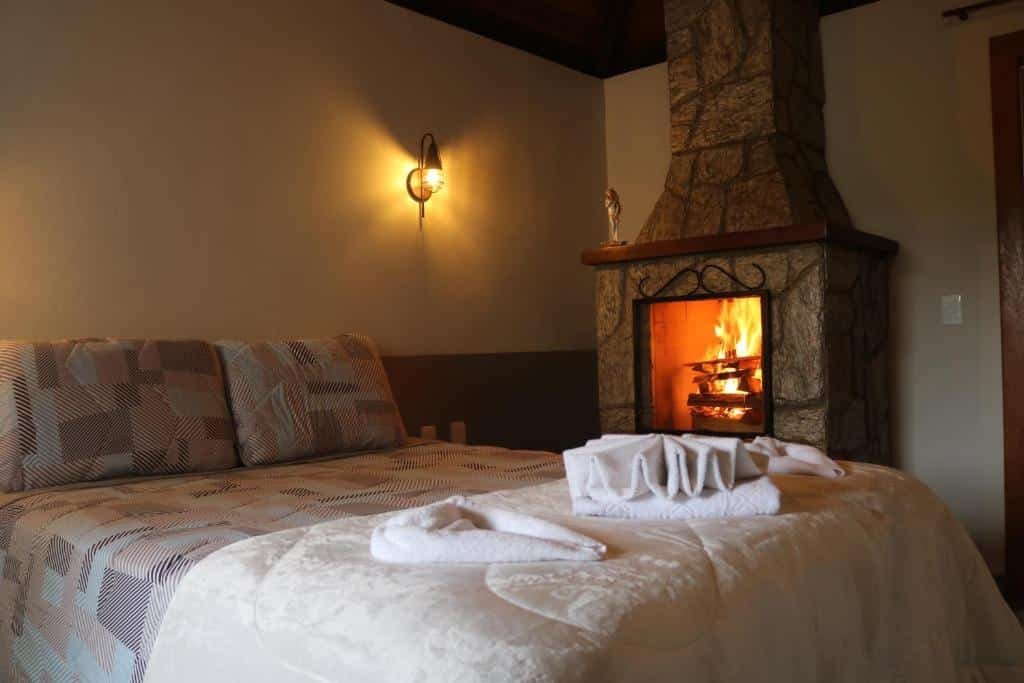 Cama de casal com toalhas em cima e lareira ao lado.