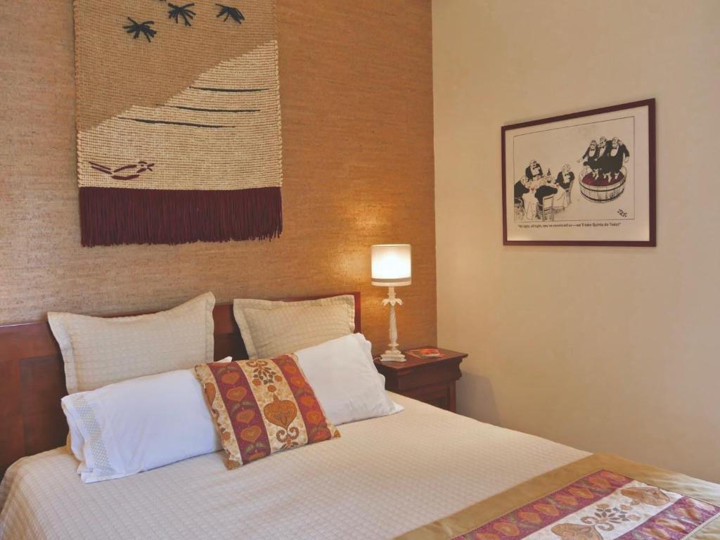 Quarto do Quinta do Tedo com cama de casal do lado esquerdo da imagem com uma cômoda com luminária do lado direito da cama. Representa hotéis no Vale do Douro.
