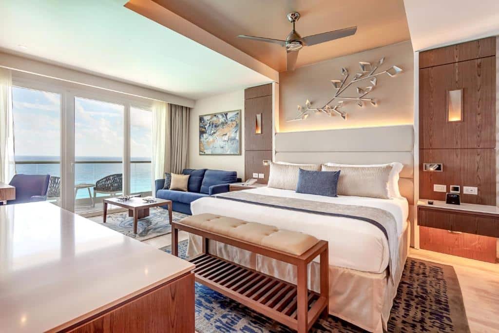 suíte com vista para o mar na sacada, além de uma área de estar e uma ampla cama de casal no Royalton CHIC Cancun