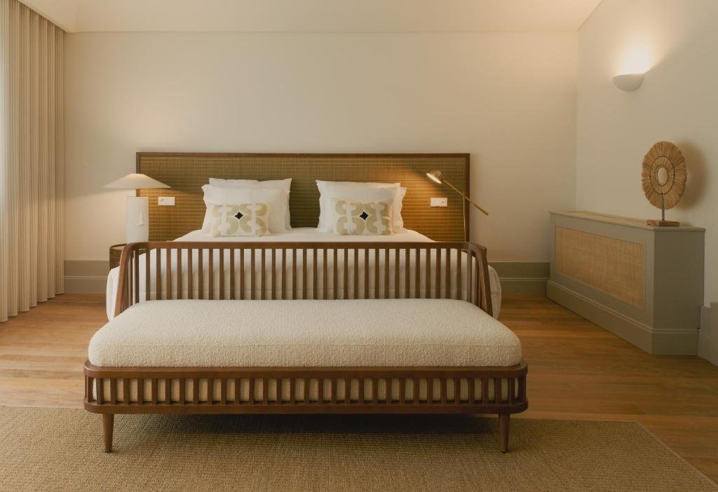 Quarto do Saboaria com cama de casal no centro do quarto e nos pés da cama um banco estofado.