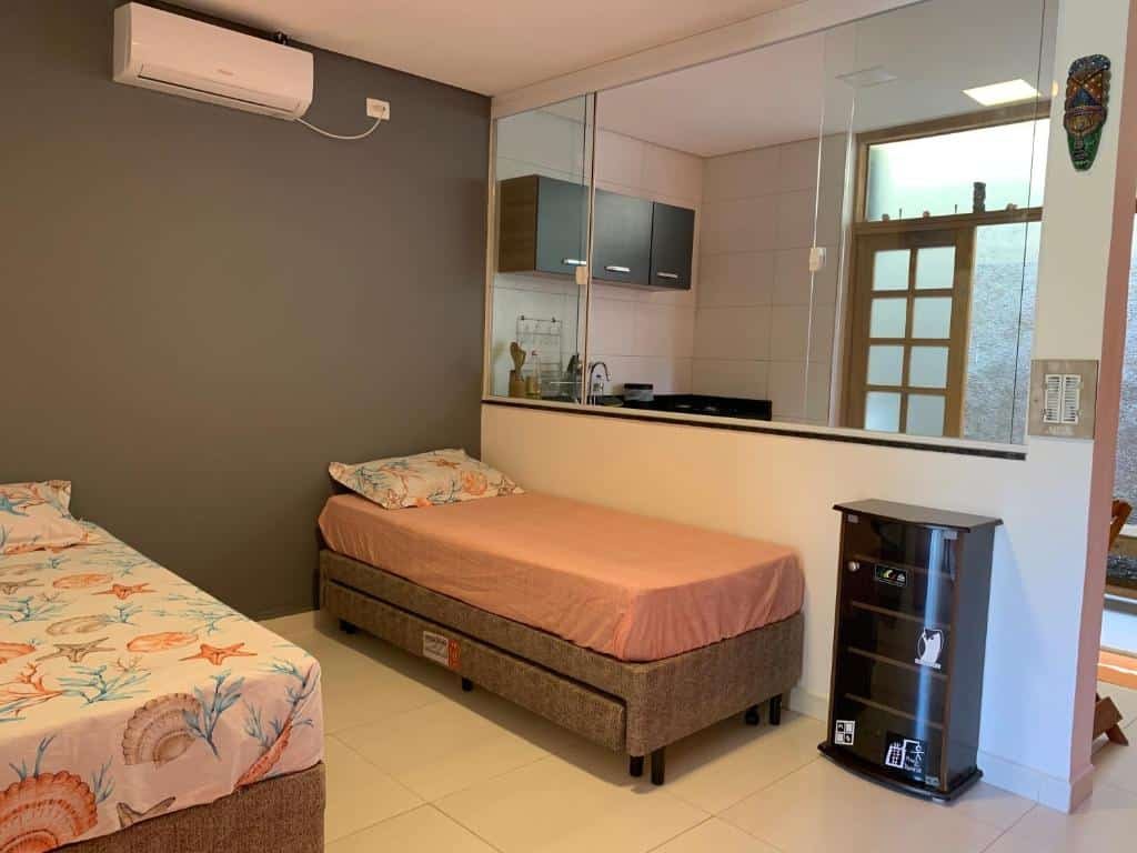 Quarto do Sunset Maresias- Casas e Chalés C1 com cama de solteiro, cama de casal e uma cozinha compcta.