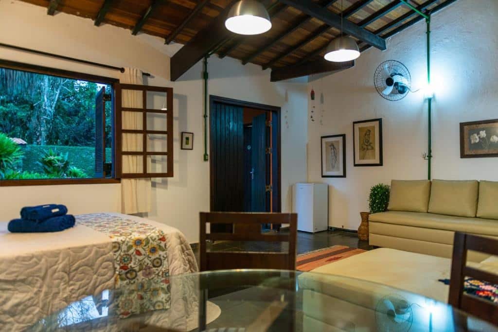 Vista do quarto em Tiê Cama e Café com cama ampla, frigobar e sofá na Praia da Juréia.