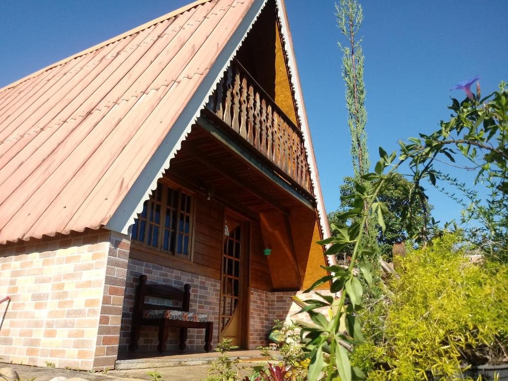Exterior do Recanto Mauá - Chalé Amor Perfeito. O chalé tem dois andares e tem formato triangular. Há árvores ao redor.