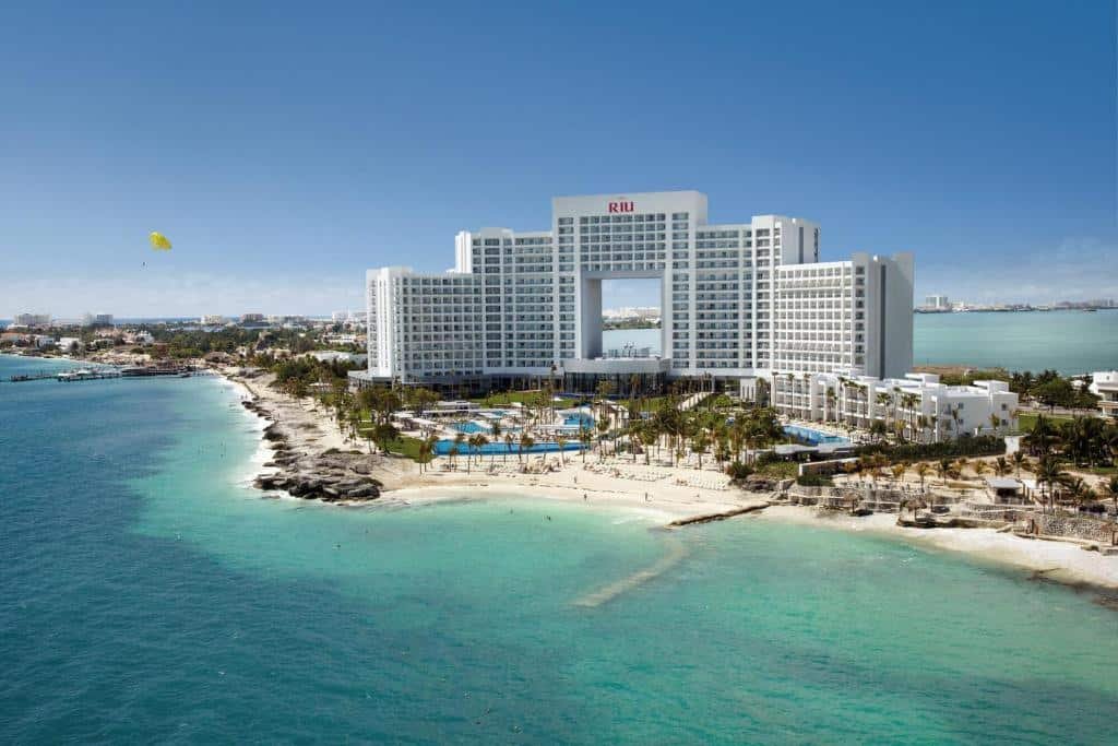 vista aerea do Riu Palace Peninsula com o mar claro em frente ao prédio e um céu azul ao fundo