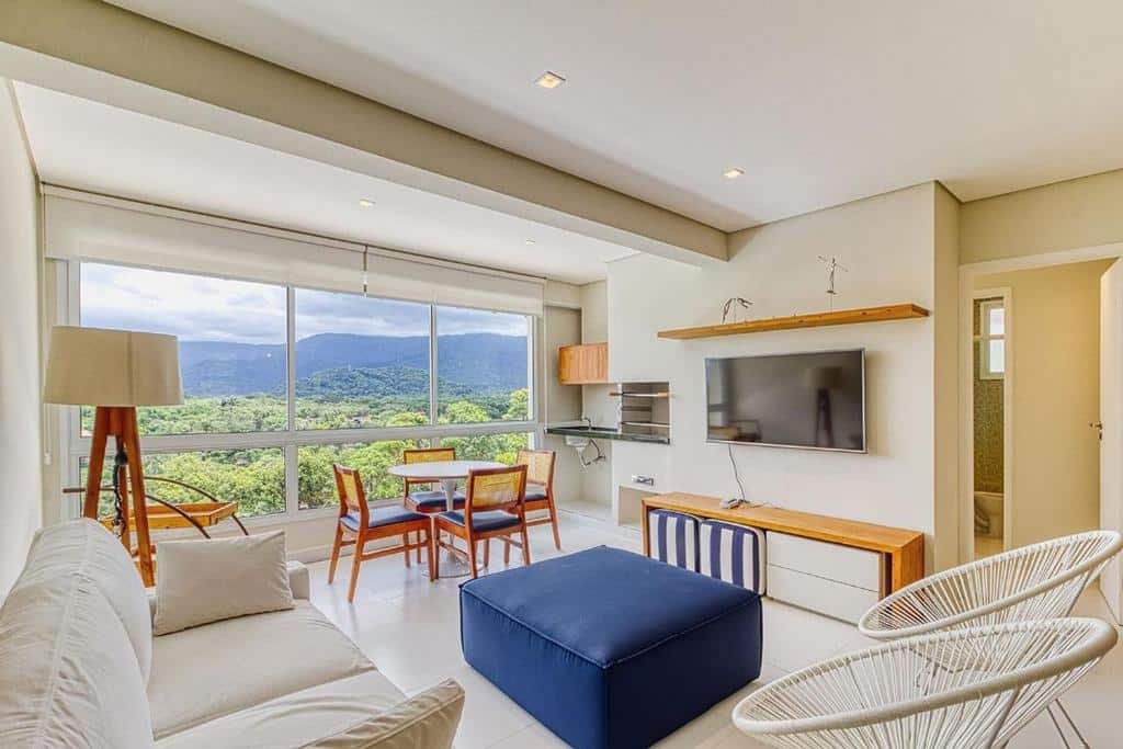 Sala do D11 - Conforto junto a natureza - Praia de Camburizinho com sofá, TV e janela ampla.